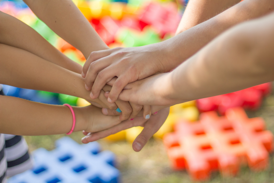 Image of young people reaching their hands into the centre in a playground. The image represets neuroaffirmative autism assessments with Diverse Directions in Northern Ireland.